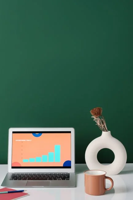 A modern workspace showing hands analyzing marketing data on a laptop and paper documents.